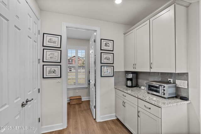 93322 Sandown Dr, Fernandina Beach, FL 32034 - kitchen with baseboards, tasteful backsplash, light wood-style floors, and white cabinetry