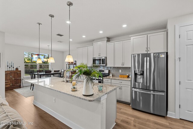 93322 Sandown Dr, Fernandina Beach, FL 32034 - kitchen with stainless steel appliances, light wood-type flooring, decorative backsplash, recessed lighting, and a kitchen island with sink