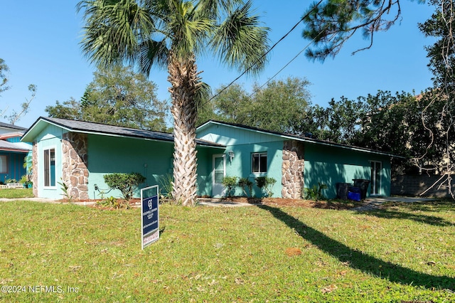 view of front facade with stone siding, a front lawn, and stucco siding