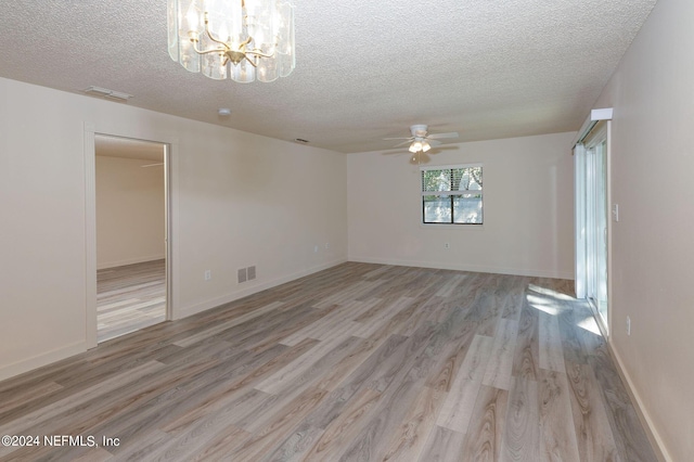 empty room with visible vents, a textured ceiling, and light wood finished floors