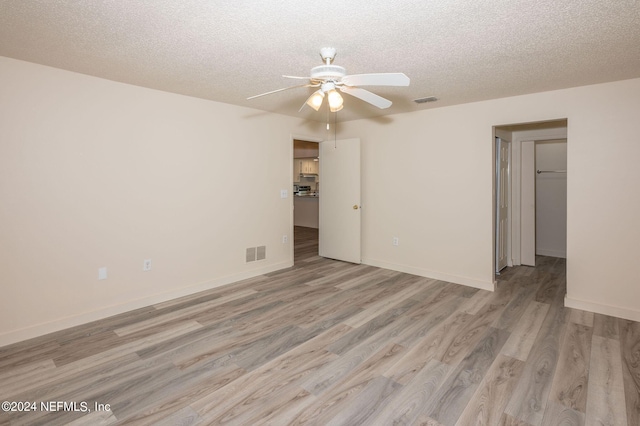 spare room featuring visible vents, a textured ceiling, and light wood finished floors