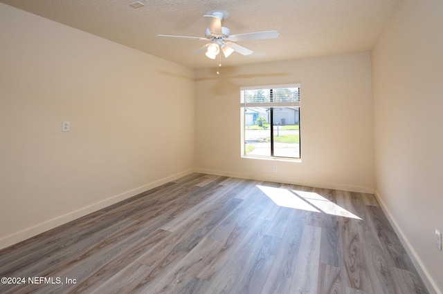 unfurnished room featuring a textured ceiling, baseboards, and wood finished floors