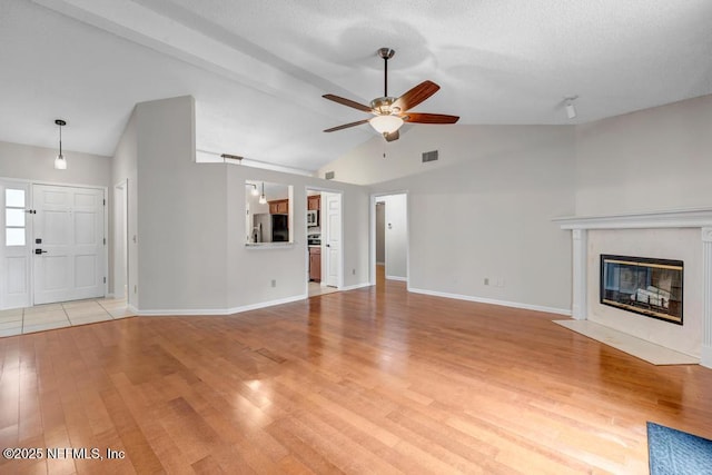 unfurnished living room with a ceiling fan, baseboards, light wood finished floors, lofted ceiling, and a fireplace