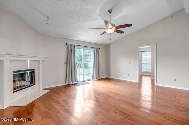 unfurnished living room featuring vaulted ceiling, light wood-style flooring, a fireplace, and ceiling fan