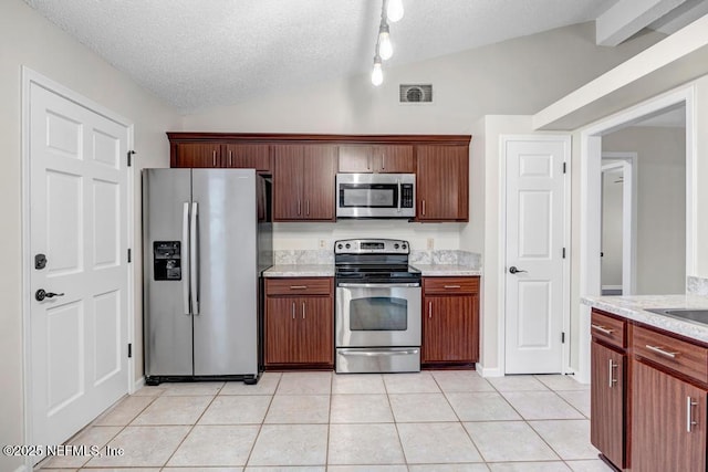 kitchen featuring light tile patterned floors, visible vents, vaulted ceiling, appliances with stainless steel finishes, and a textured ceiling