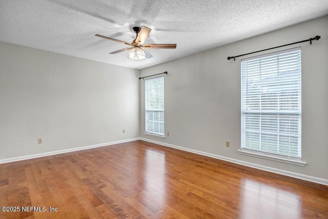 unfurnished room featuring a ceiling fan, wood finished floors, baseboards, and a textured ceiling