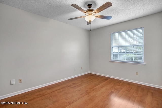 spare room featuring a textured ceiling, a ceiling fan, baseboards, and wood finished floors