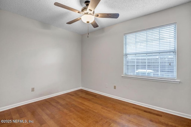 spare room with wood finished floors, a ceiling fan, baseboards, and a textured ceiling