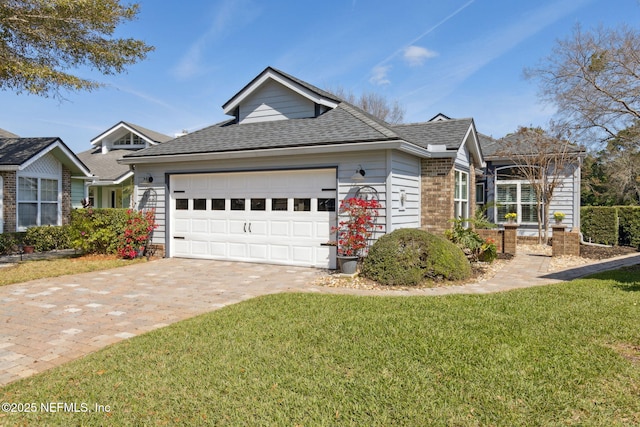 ranch-style home with a garage, a shingled roof, decorative driveway, a front yard, and brick siding