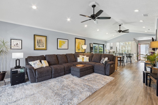 living area featuring baseboards, visible vents, wood finished floors, vaulted ceiling, and crown molding