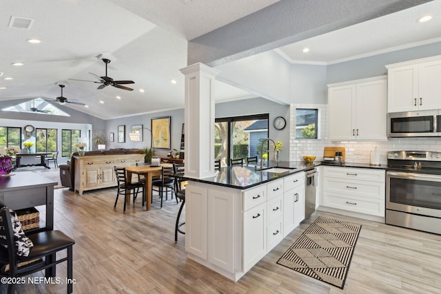 kitchen featuring stainless steel appliances, open floor plan, a healthy amount of sunlight, a sink, and ornate columns