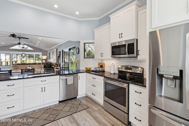 kitchen featuring stainless steel appliances, a sink, white cabinets, ornamental molding, and tasteful backsplash