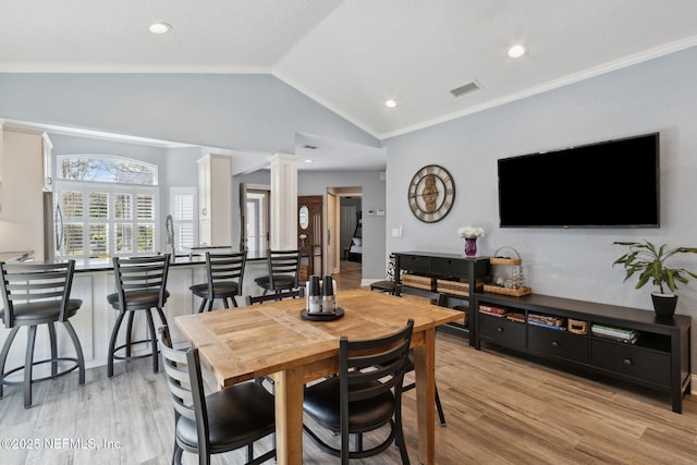 dining space with light wood-style floors, visible vents, vaulted ceiling, and ornate columns