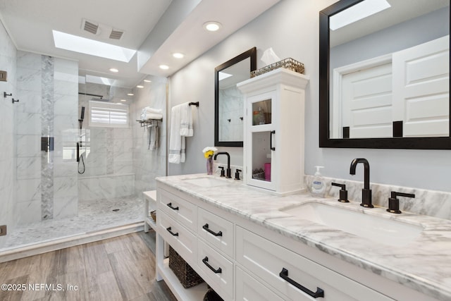 full bathroom featuring double vanity, a marble finish shower, a sink, and recessed lighting