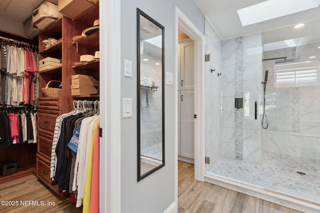 walk in closet with a skylight and wood finished floors