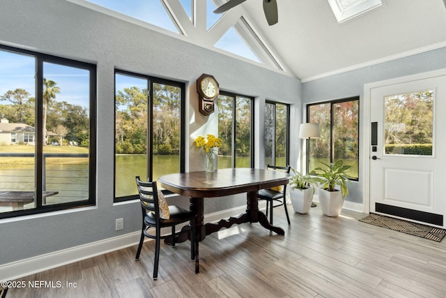 sunroom / solarium featuring vaulted ceiling with skylight and a ceiling fan