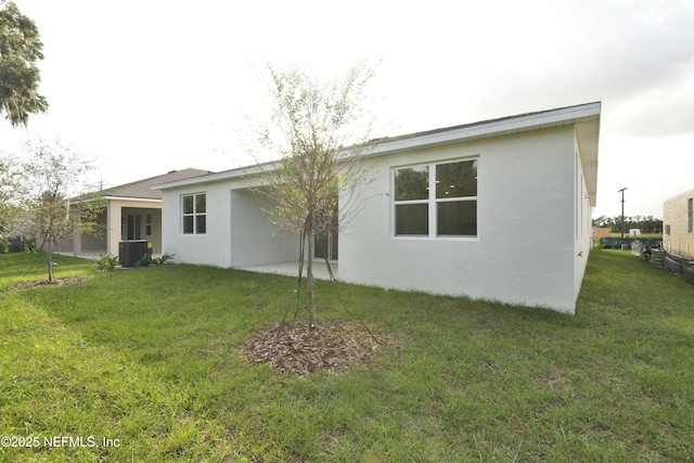 back of house with cooling unit, a lawn, and stucco siding