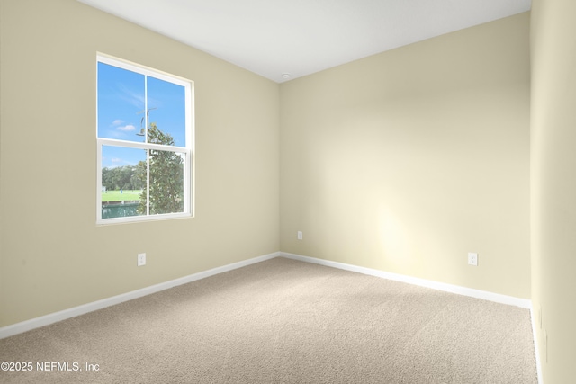 carpeted empty room featuring baseboards