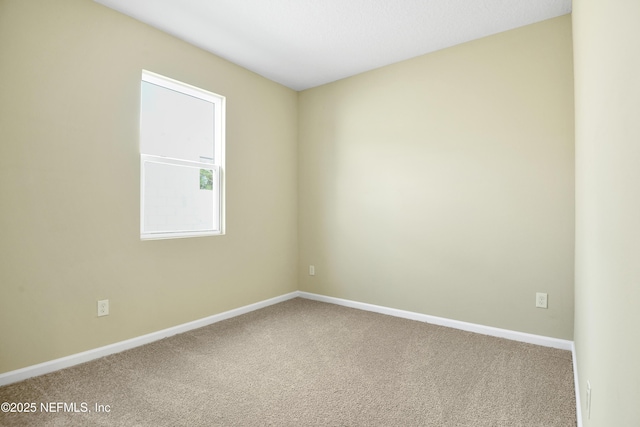 empty room featuring carpet and baseboards