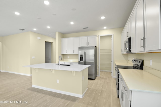 kitchen with a kitchen island with sink, white cabinetry, stainless steel appliances, and a sink