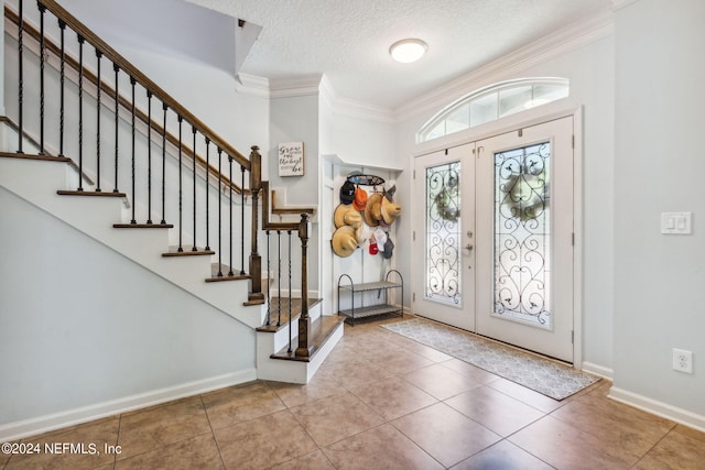 tiled foyer featuring ornamental molding, french doors, a textured ceiling, and baseboards