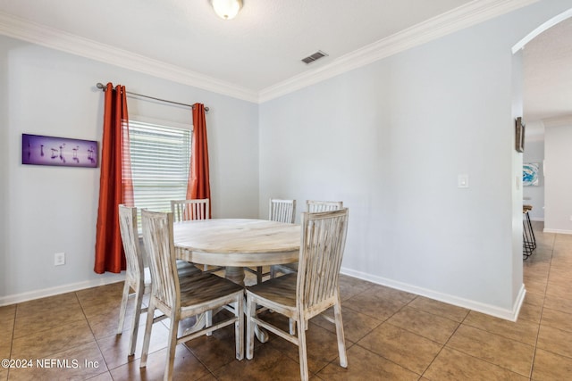 dining room featuring arched walkways, visible vents, baseboards, ornamental molding, and tile patterned floors