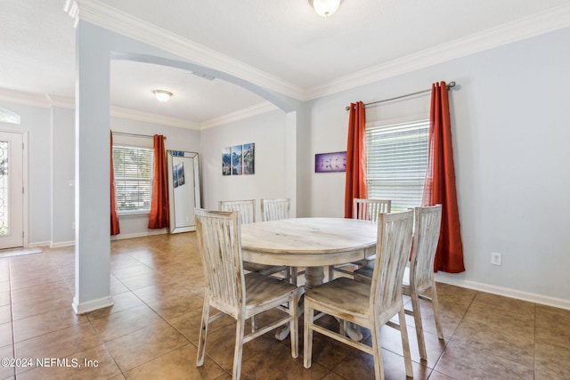 dining area featuring light tile patterned floors, baseboards, arched walkways, and ornamental molding