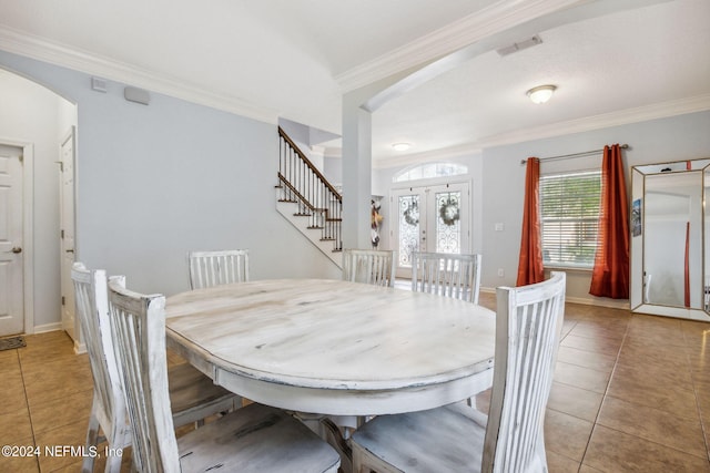 dining room featuring arched walkways, crown molding, and light tile patterned floors