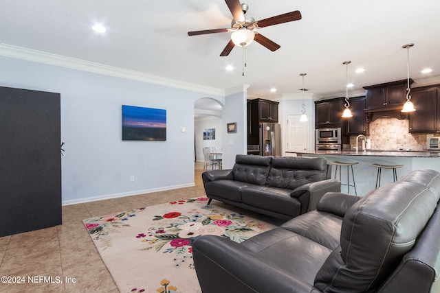 living room featuring arched walkways, light tile patterned floors, baseboards, and crown molding