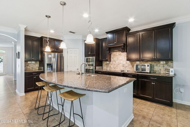 kitchen with visible vents, dark stone counters, a breakfast bar area, stainless steel appliances, and a sink