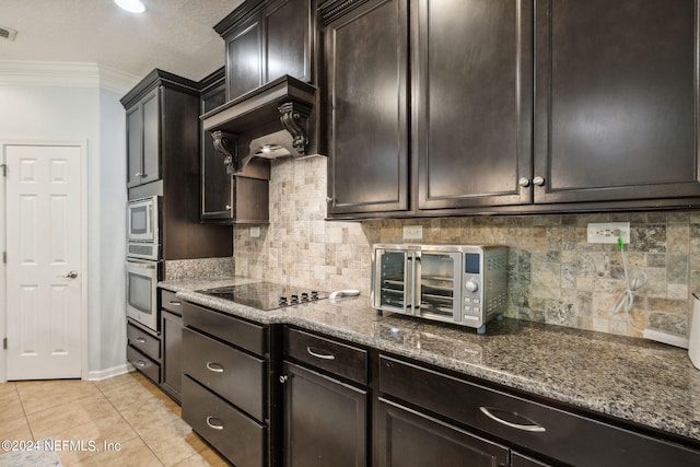 kitchen with light tile patterned floors, stainless steel appliances, ornamental molding, backsplash, and dark stone countertops