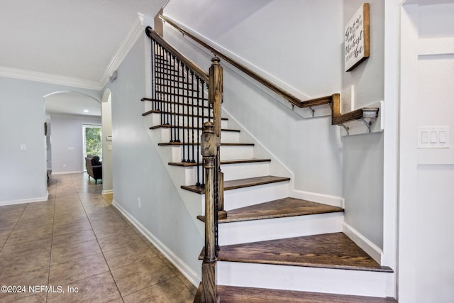 stairs with ornamental molding, arched walkways, tile patterned flooring, and baseboards