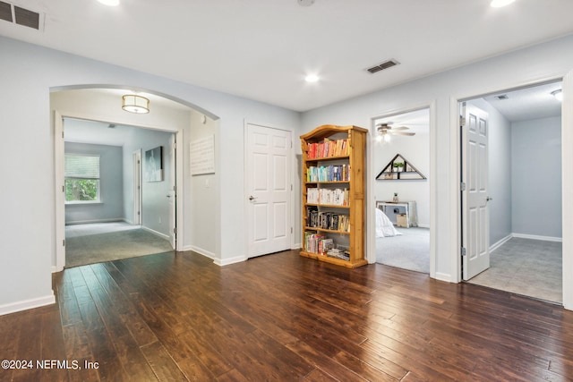 empty room featuring arched walkways, wood-type flooring, and visible vents