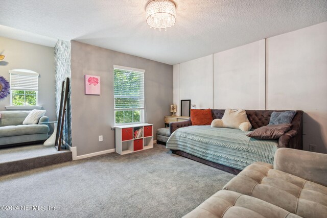 carpeted bedroom featuring an inviting chandelier, baseboards, and a textured ceiling