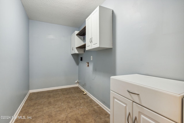 washroom featuring cabinet space, baseboards, washer hookup, and a textured ceiling