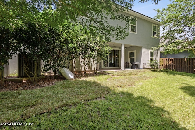 rear view of house featuring a patio area, fence, a lawn, and stucco siding