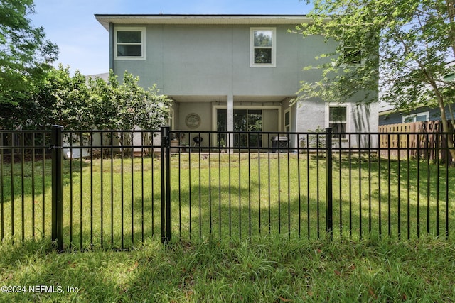 rear view of property with a lawn, fence private yard, and stucco siding