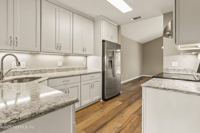 kitchen with a sink, visible vents, wall chimney range hood, stainless steel fridge with ice dispenser, and light wood finished floors