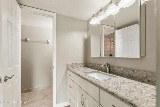 bathroom featuring tile patterned floors, baseboards, tiled shower, and vanity