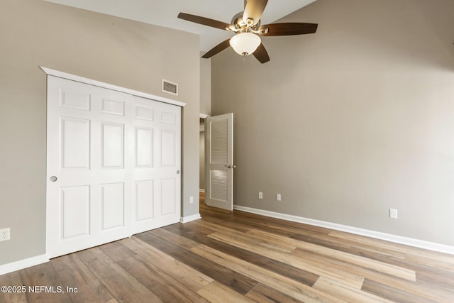 unfurnished bedroom featuring baseboards, a closet, visible vents, and wood finished floors