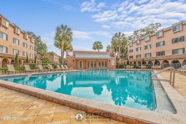 community pool featuring french doors, a patio area, and fence