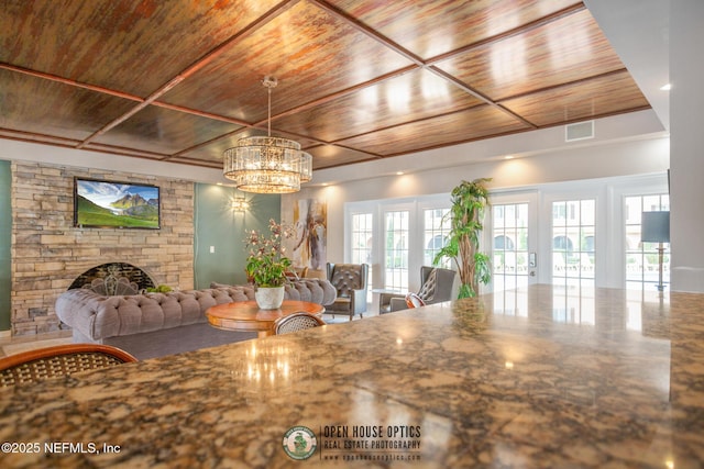 unfurnished dining area featuring french doors, a fireplace, visible vents, wood ceiling, and a chandelier