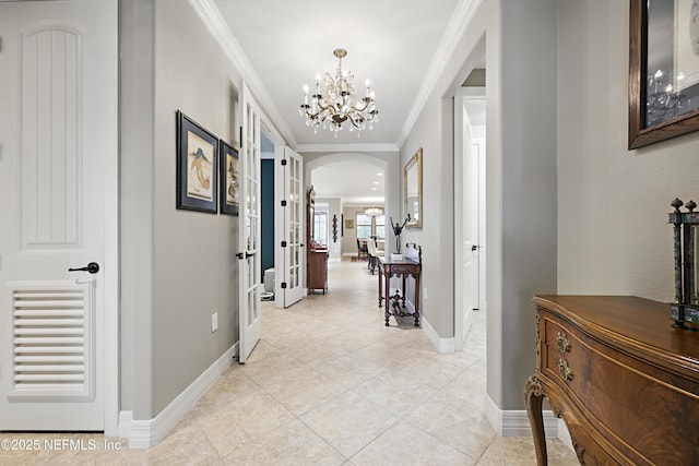 corridor featuring ornamental molding, arched walkways, a notable chandelier, and baseboards