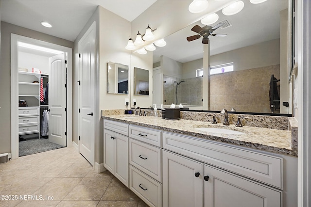 bathroom with double vanity, a spacious closet, a stall shower, and a sink