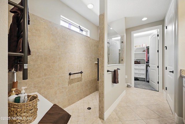 bathroom featuring baseboards, tile patterned flooring, a spacious closet, a walk in shower, and recessed lighting