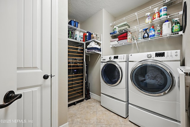 washroom featuring laundry area, a textured ceiling, washing machine and clothes dryer, and light tile patterned floors