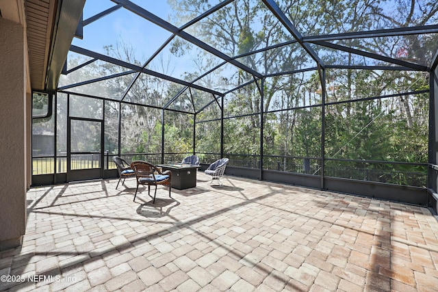 view of patio with glass enclosure and a fire pit