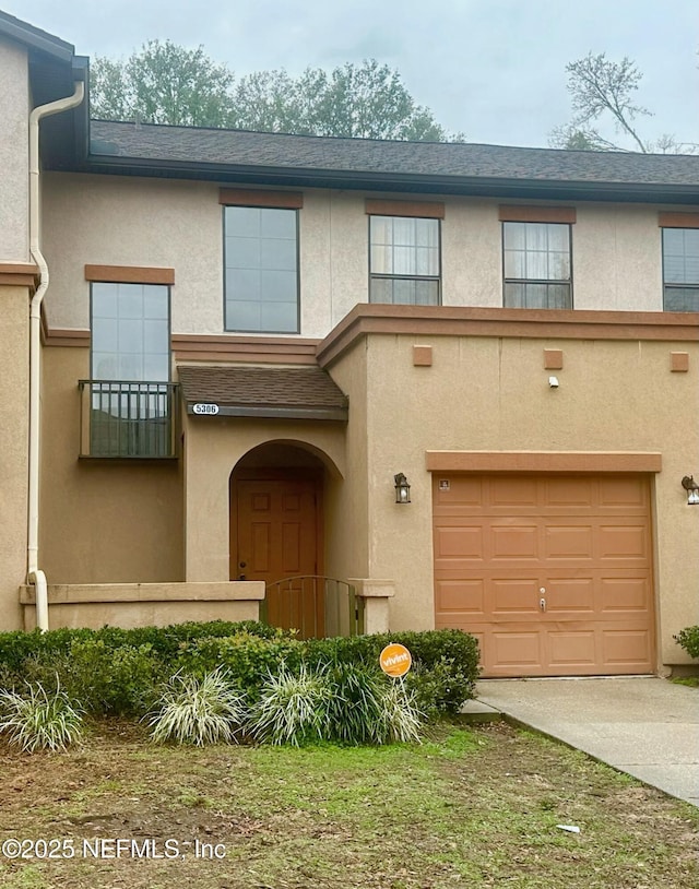 multi unit property featuring a garage, concrete driveway, a shingled roof, and stucco siding