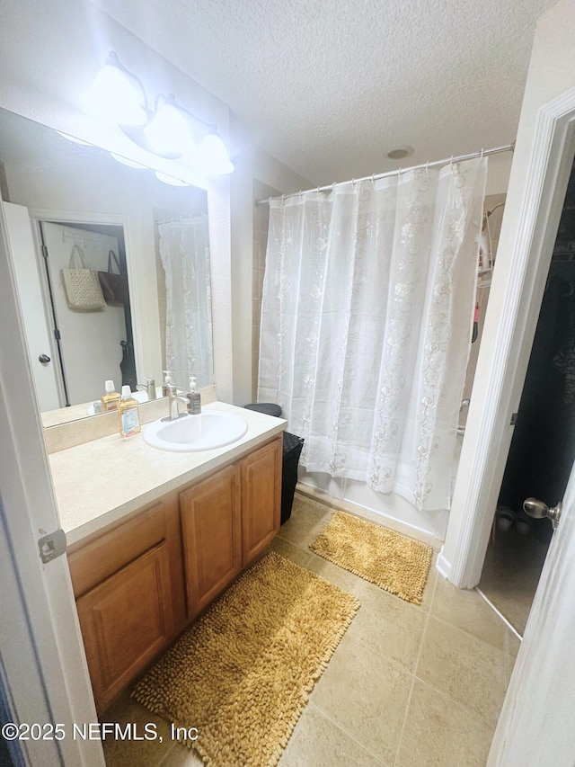 bathroom featuring a textured ceiling, shower / bath combo with shower curtain, vanity, and tile patterned floors