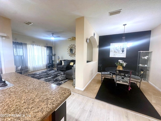 dining space featuring a textured ceiling, light wood finished floors, visible vents, and baseboards